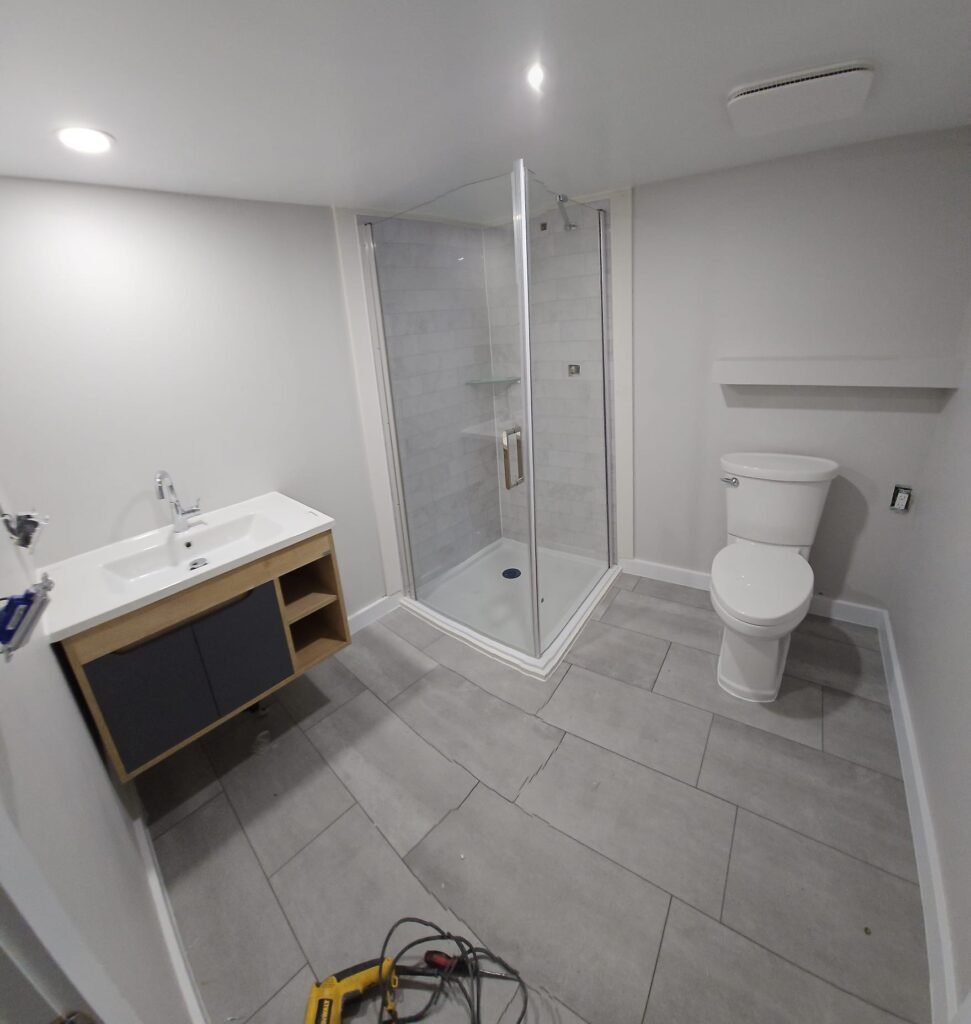 Basement bathroom renovation with glass shower and modern vanity