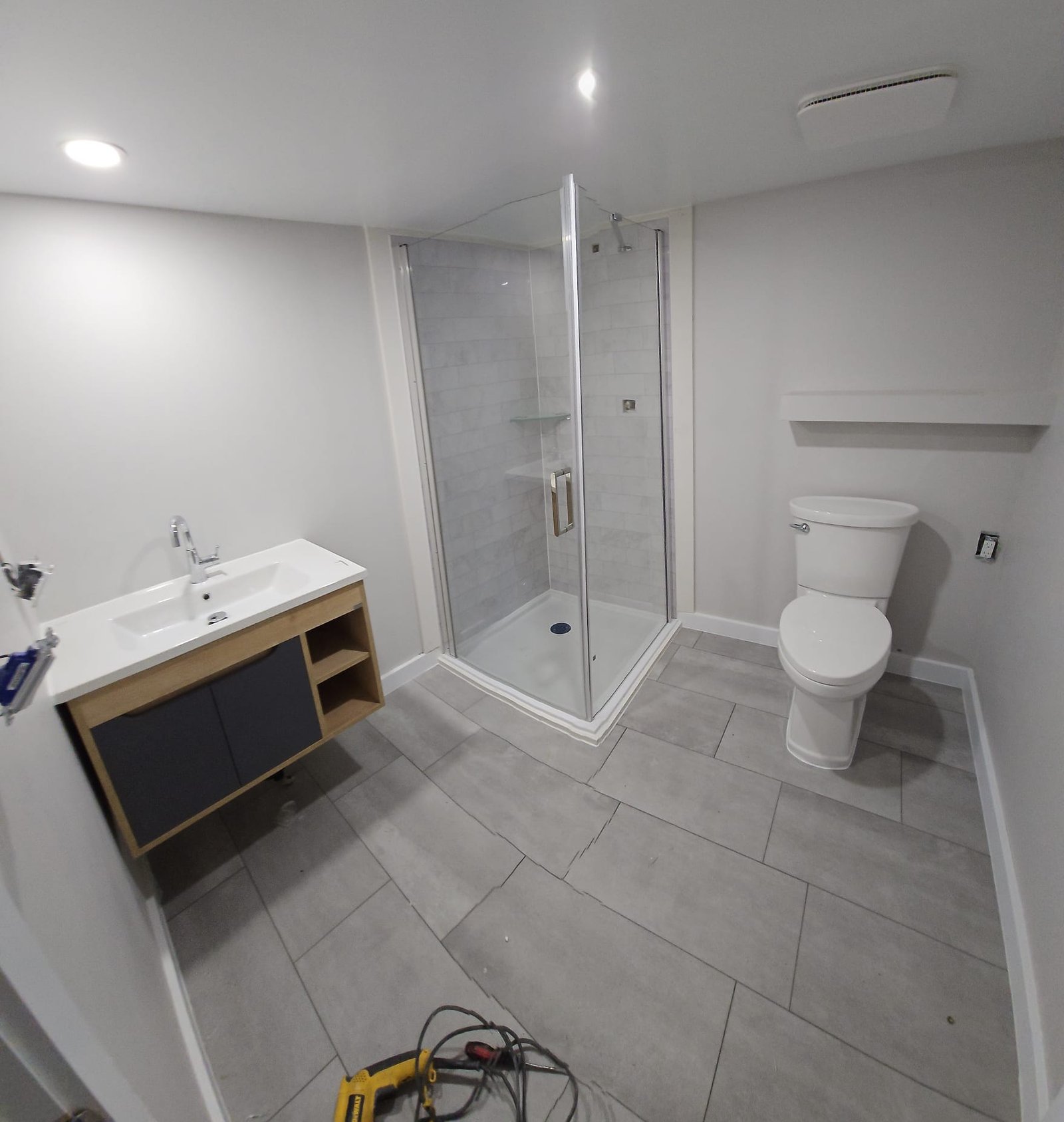 Basement bathroom renovation with glass shower and modern vanity