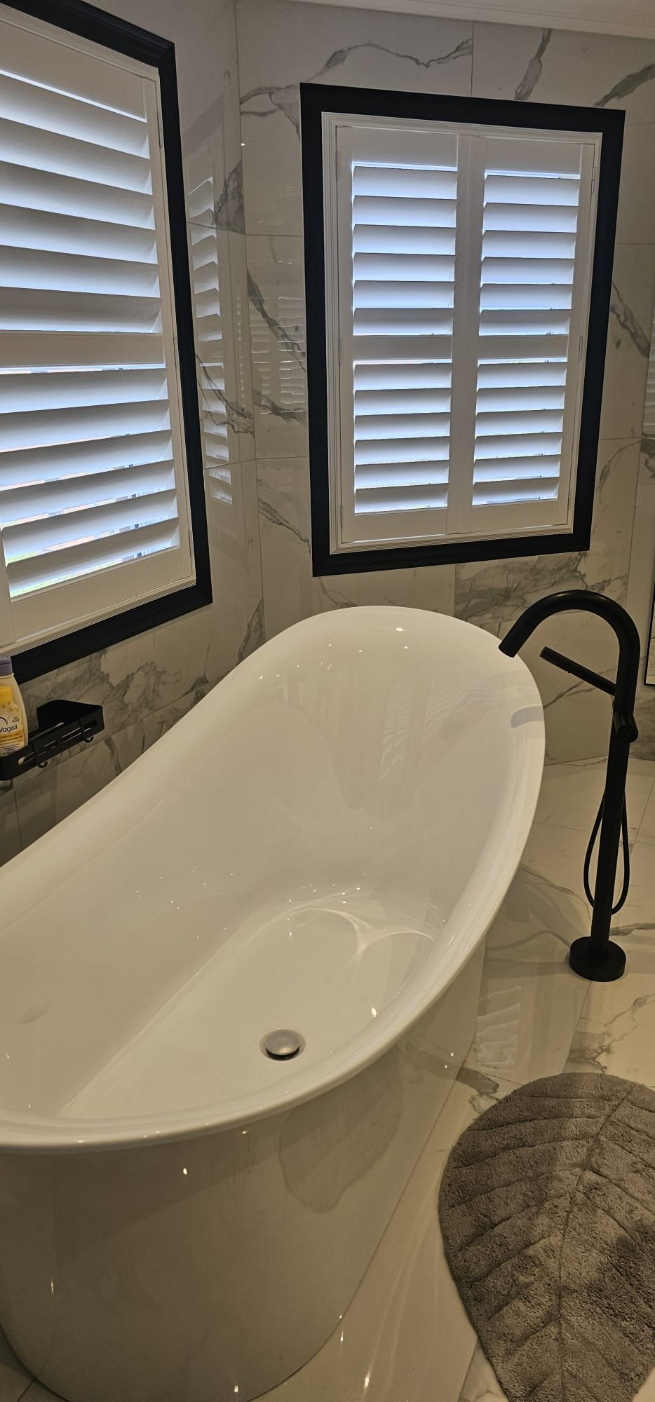 Freestanding tub with marble surround and plantation shutters