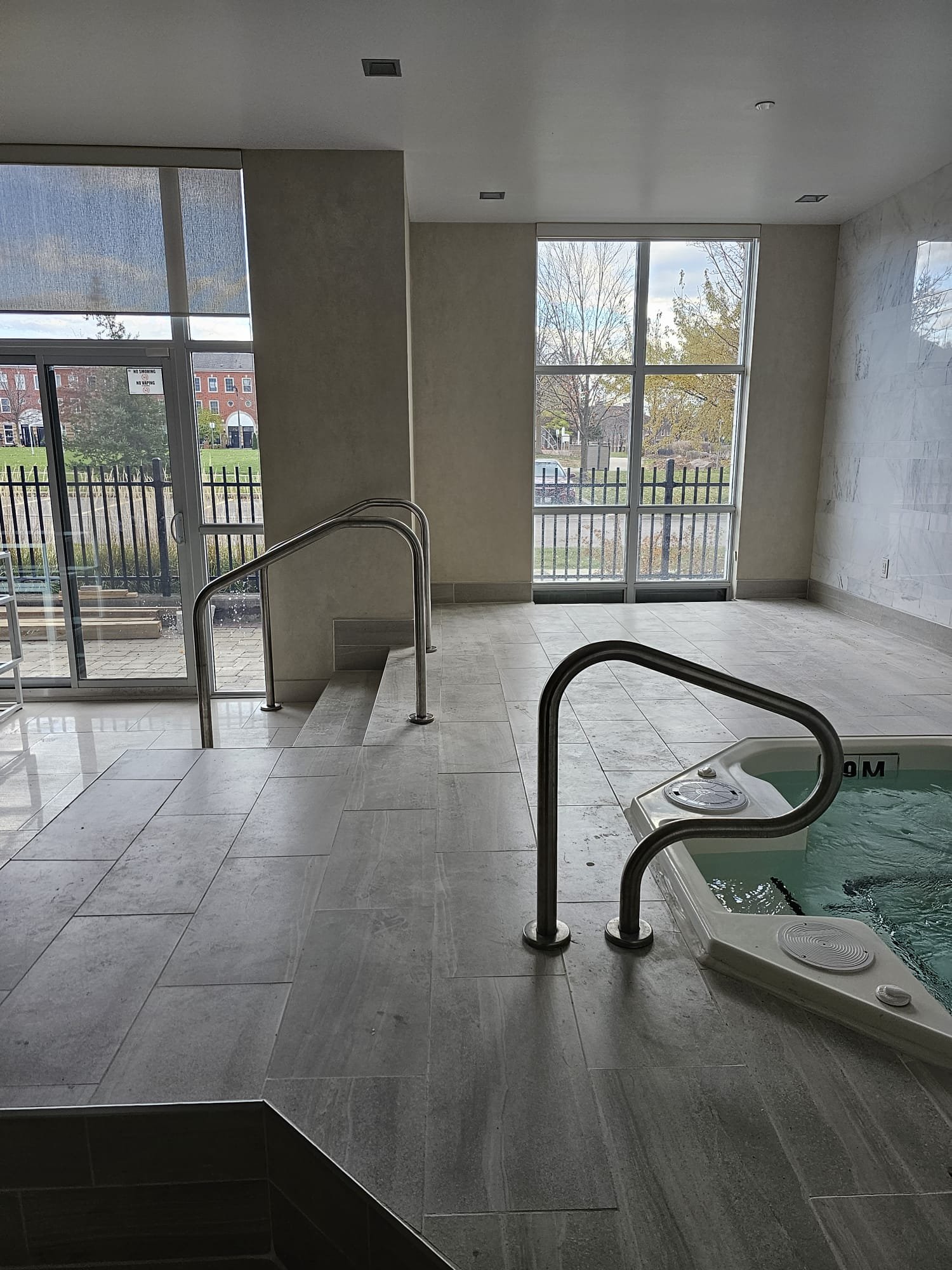 Commercial indoor pool and spa with floor-to-ceiling glass windows