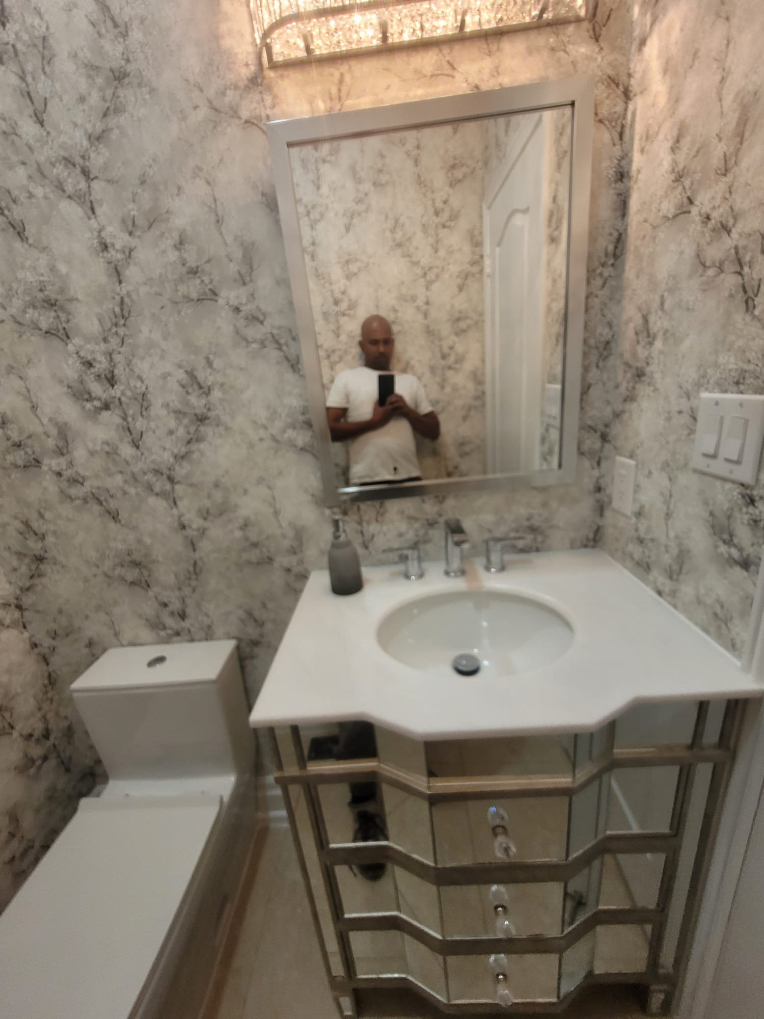 Powder room renovation with ornate vanity and designer wallpaper